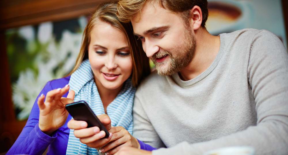 Deux clients souriants consultent une enquête de satisfaction sur un smartphone